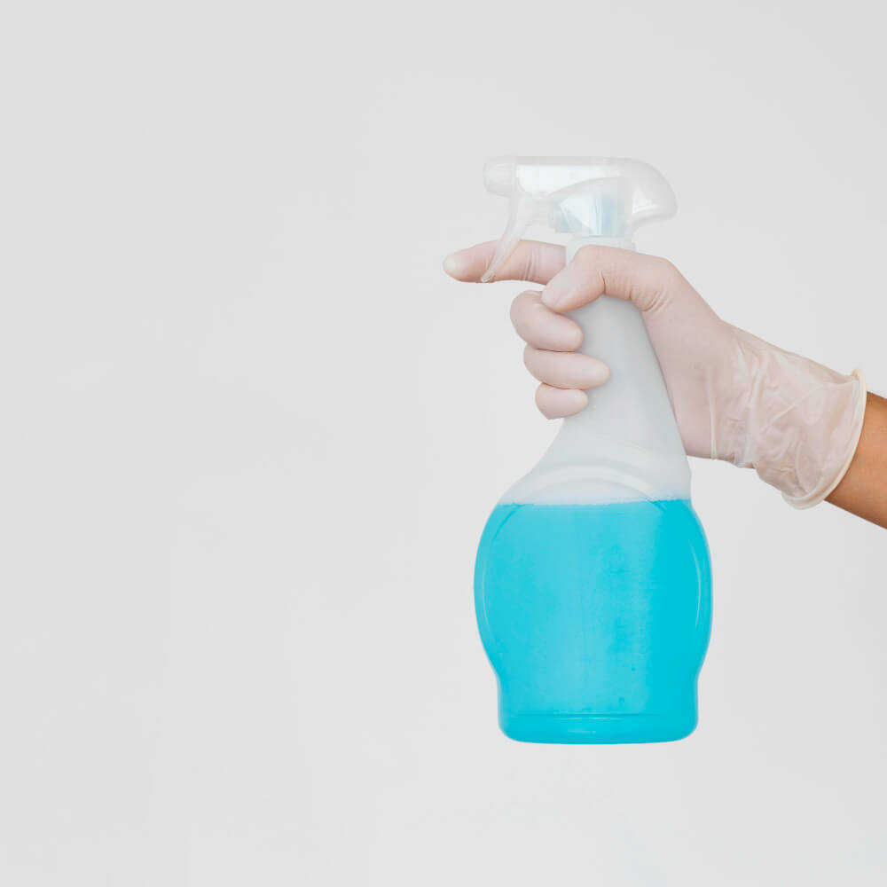 Cleaner holding an eco-friendly glass chemical spray bottle