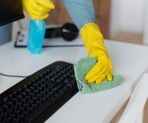 An office cleaner wiping a keyboard using eco-friendly cleaning product