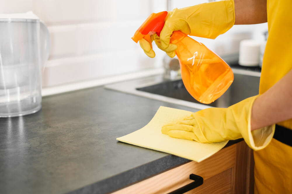 Cleaner wiping a kitchen top with eco-friendly disinfectant