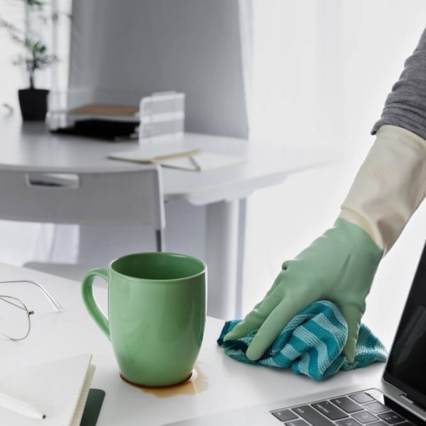 An office cleaner wiping a coffee spill on a work desk