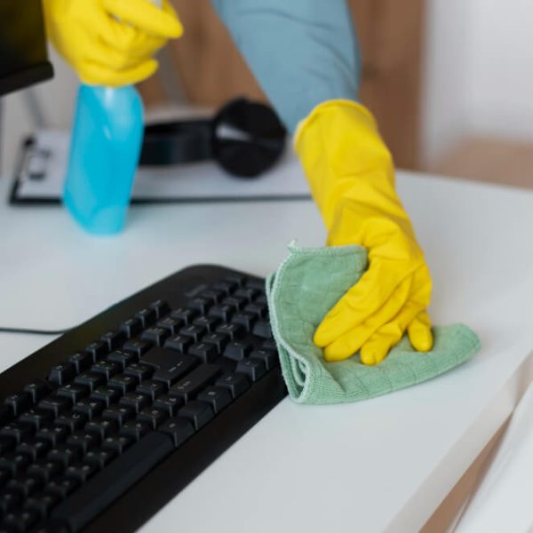 An office cleaner wiping a keyboard using eco-friendly cleaning product