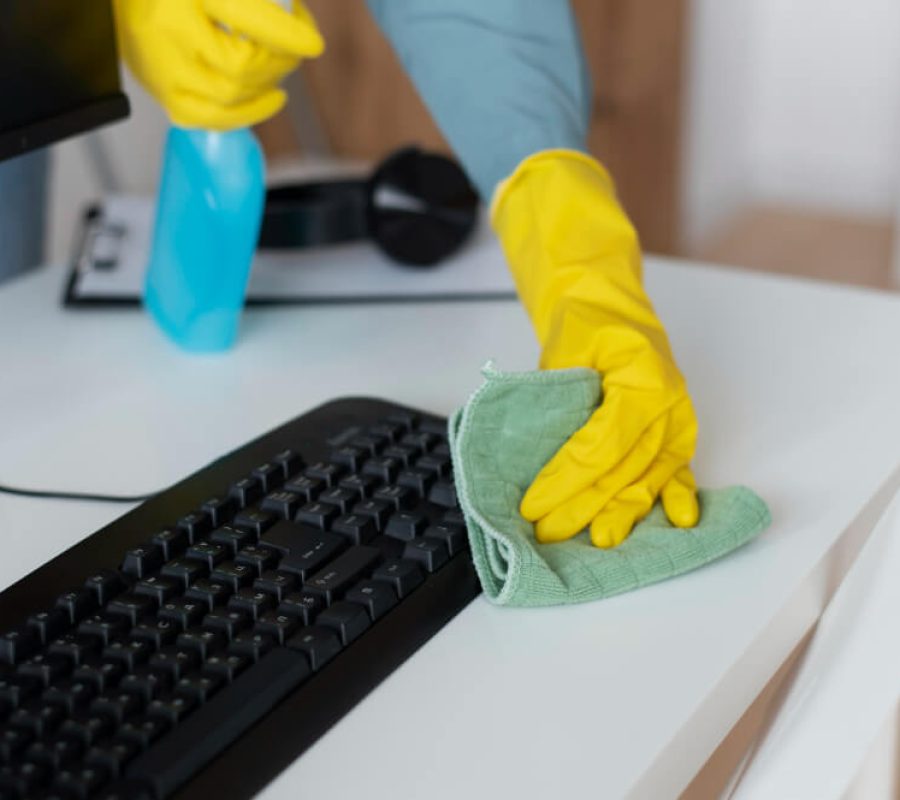 An office cleaner wiping a keyboard using eco-friendly cleaning product