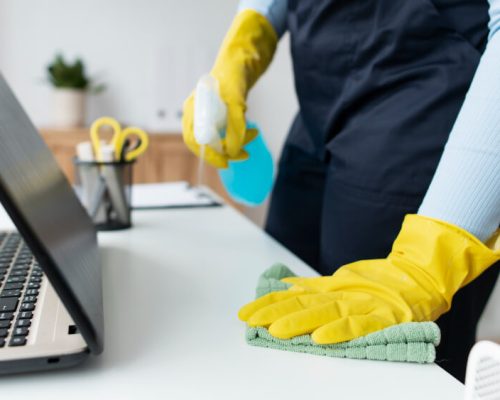 office cleaner disinfecting a workdesk